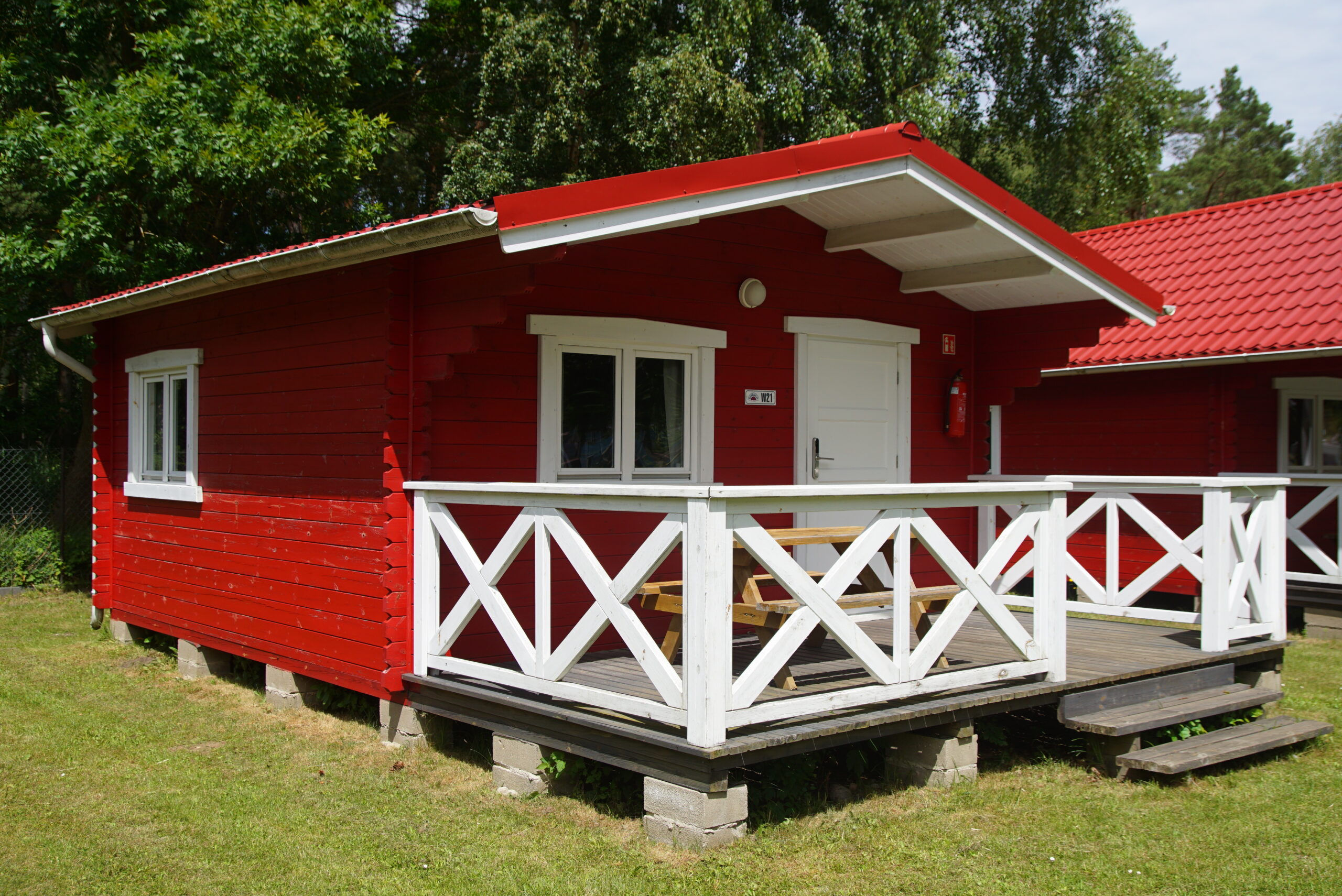 Strefa wypoczynku przy domku na campingu InterCamp’84 Łeba – drewniana ławka, zieleń i spokojne otoczenie, idealne na relaks.