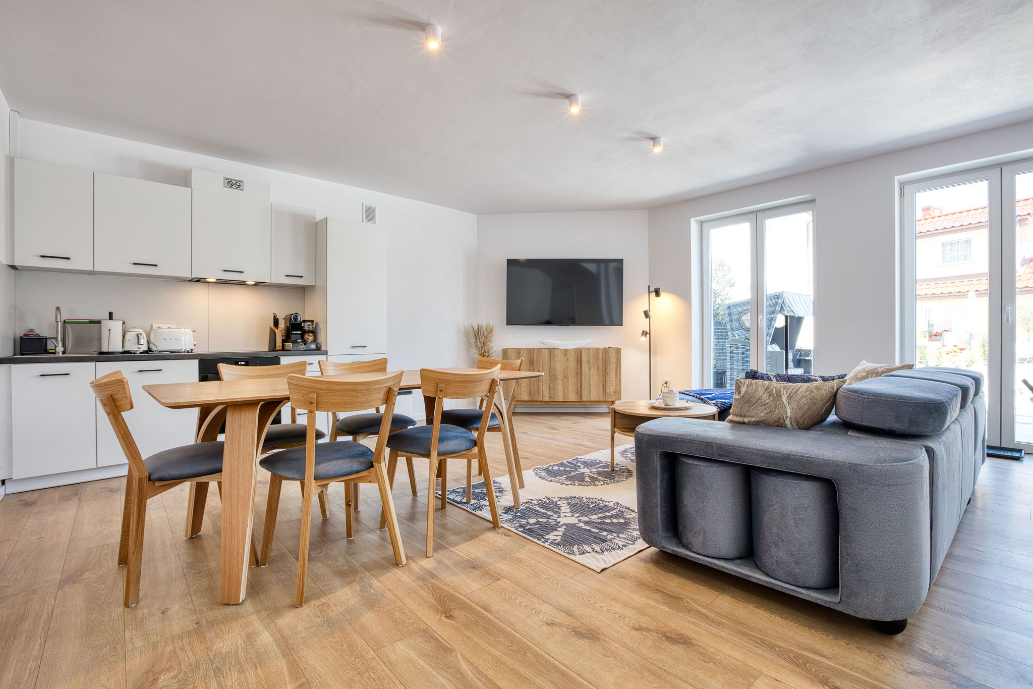 Przestronny salon z kuchnią w rodzinnym apartamencie Villa Supreme Łeba – nowoczesne wnętrza i wysoki standard wypoczynku.